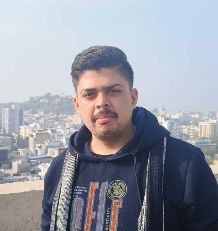 Portrait of Harsh Agarwal on a rooftop with the city behind him